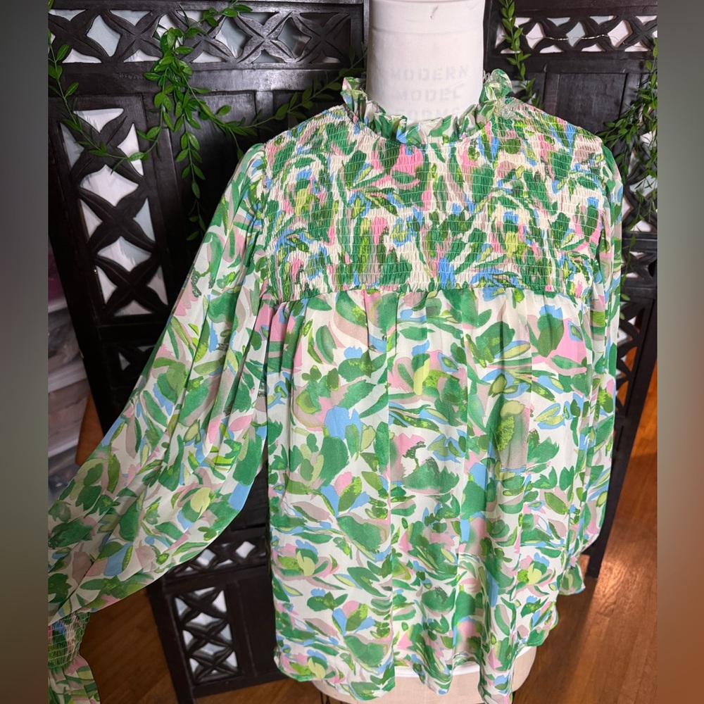 Entro, smocked yoke; high neck and long sleeves with elastic cuffs;